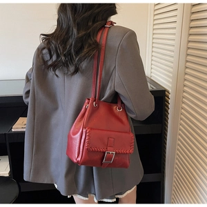 Détail du sac seau rouge montrant les bords surjetés et la boucle sur la poche avant