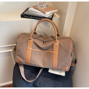 Detail of a large brown canvas travel bag with leather straps on a blue velvet chair