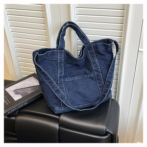 Detailed macro view of dark blue denim tote bag with white contrast stitching and pocket