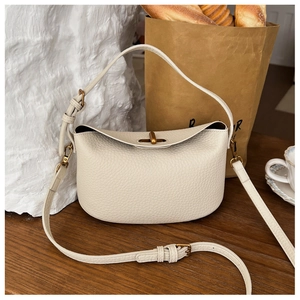 Detail of creamy white pebble grain leather bag featuring a gold metal bar twist lock