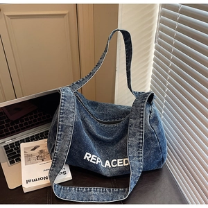 Detail view of deep blue denim tote bag with REPLACED print and wide shoulder strap