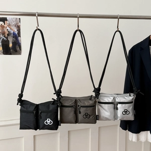 Detailed display of nylon shoulder bags in black, grey, and silver hanging on a metal rack