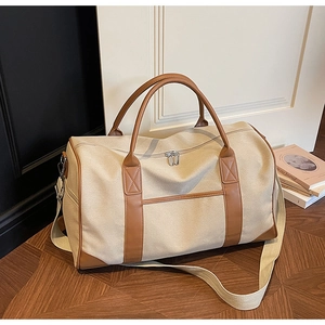 Detail view of large beige canvas and brown leather travel bag with adjustable strap