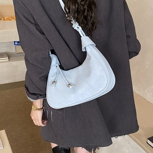 Detail of light blue leather hobo bag with knotted strap and metal tassel detail