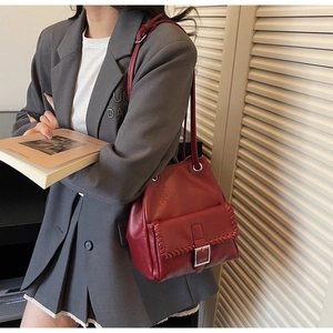 Détail du sac bandoulière bordeaux vintage avec coutures contrastées et boucle argent
