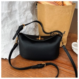 Close-up of litchi grain leather texture and gold buckle on a black crescent bag