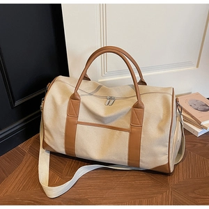 Large beige canvas travel duffel bag with brown leather handles and wide shoulder strap