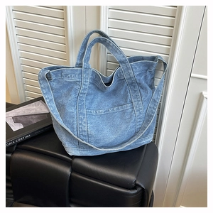 Detail of large denim tote bag featuring white contrast stitching and outer pocket