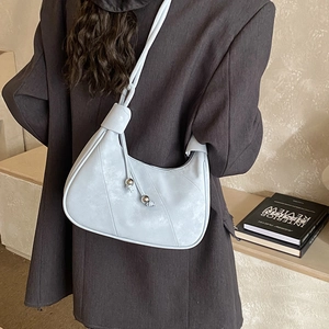 Detail view of light blue leather half-moon bag with elegant stitching and silver metal beads