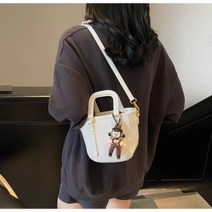 Sac seau blanc minimaliste avec un pendentif poupée mignon et une bandoulière amovible