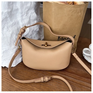 Detailed macro view of beige lychee grain leather handbag with matte gold twist lock