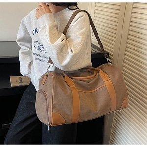Close-up of brown canvas travel bag showing leather reinforcements and side zipper pocket