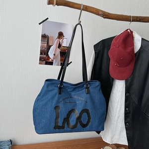 Detail of denim tote bag with leather handles and Carry Your Joy Everywhere slogan print