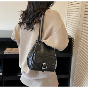 Détail du sac seau en cuir noir avec boucle en métal argenté et surpiqûres contrastées