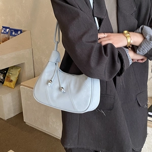 Close-up of light blue underarm bag with curved pleats and metal bead drawstring details