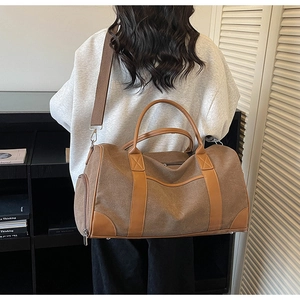 Detail view of large brown canvas travel bag with leather handles and wide shoulder strap