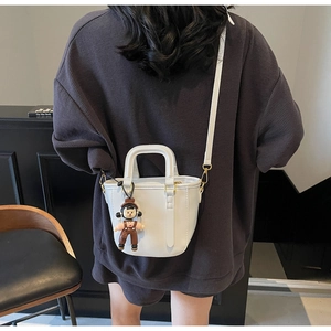 Vue détaillée du dos d'un sac seau blanc porté, avec un accessoire de figurine de dessin animé