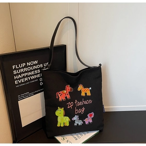 Detailed view of colorful cartoon animal embroidery on a black canvas tote bag