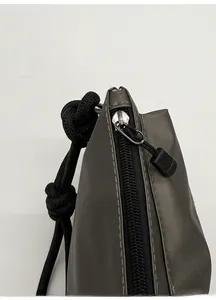 Close-up of durable metal zipper with black cord puller on a gray nylon shoulder bag
