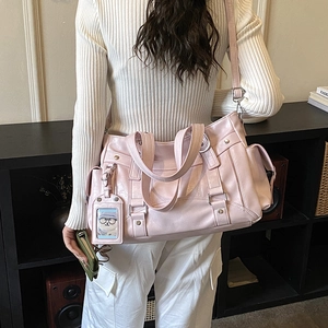 Dettaglio della borsa tote rosa con tasche multiple e ciondolo a orso su una modella