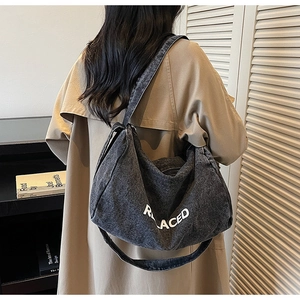 Detailed back view of a model wearing a dark grey denim tote bag with white lettering