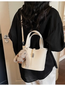 Bolso cubo de cuero beige con asas superiores y un lindo colgante de conejo