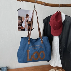 Detail of blue denim tote bag with leather straps and inspirational typography print