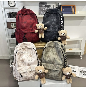 Vista dettagliata di quattro zaini scolastici in vari colori con ciondoli a forma di orso