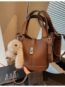 Elegante bolso de cubo de cuero marrón oscuro con cierre plateado y colgante de conejo