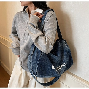 Detail of the large washed denim tote bag showing the REPLACED white letter printing