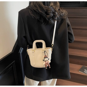 Détail du sac seau blanc crème avec pendentif mignon et texture en similicuir