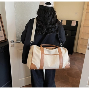 Detail of canvas travel bag with leather accents showing large capacity and shoulder strap