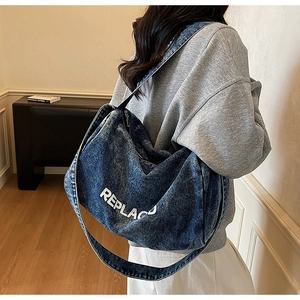 Detail of blue washed denim tote bag showing distressed texture and wide strap