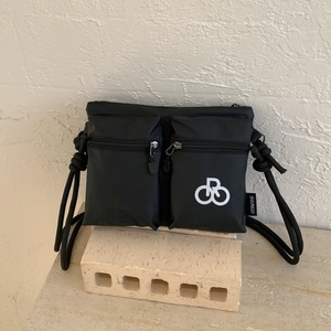 Detail of black nylon crossbody bag with dual zipper pockets and rope shoulder strap