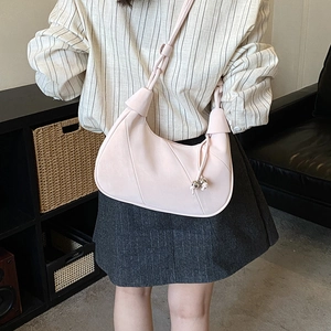 Light pink suede-like crescent shoulder bag with knot detail and beaded tassel decoration