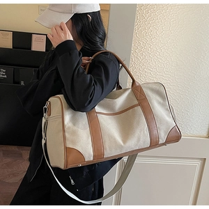 Detailed shot of large canvas travel bag with leather accents shown on a model