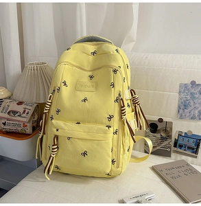 Dettaglio dello zaino in tela beige con motivi a farfalla e cerniera con nappe intrecciate