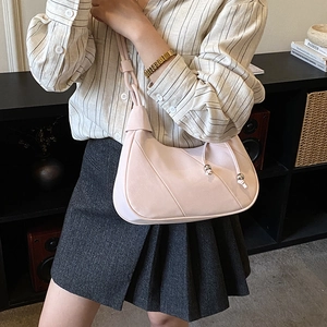 Detail of quilted underarm bag featuring leather knot strap and silver bead accents
