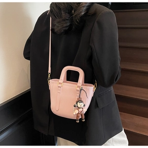 Vue détaillée du mini sac seau rose en cuir lisse avec un pendentif charmant