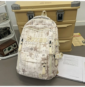 Close-up of canvas school backpack featuring plaid pattern and star prints with KPXBD embroidery