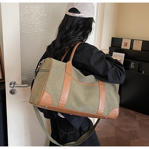 Detail view of army green canvas travel bag with brown leather trim and shoulder strap