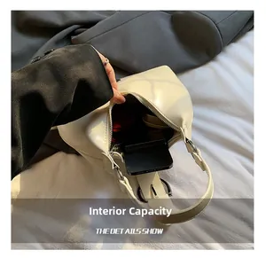Internal capacity of minimalist off-white shoulder bag showing phone and cosmetics