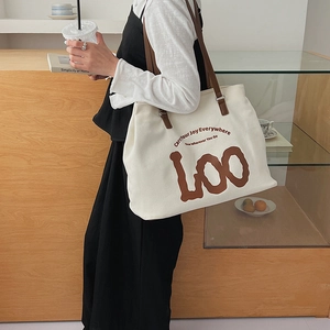 Detail of canvas tote bag with leather handles and Carry Your Joy Everywhere text