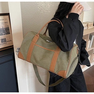 Olive green canvas travel bag with brown leather trim and adjustable shoulder strap