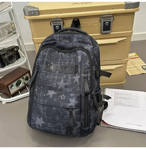 Detail of grey star-pattern backpack with KPXBD lettering and adjustable side buckles