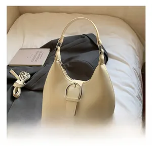 Chic cream dumpling bag with silver buckle shown on a bed with a book and blazer