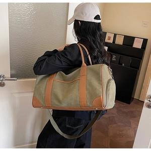 Rear view of a model carrying a large army green canvas travel bag with brown leather trim