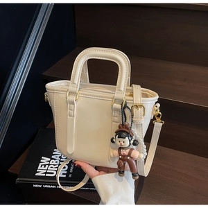Détails d'un sac seau blanc crème avec pendentif poupée et chaîne décorative en perles