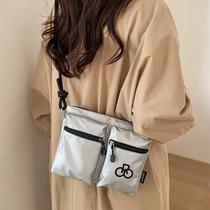 Close-up of metallic silver nylon crossbody bag showing dual zipper pockets and logo detail