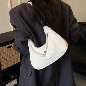 Detail view of the white leather crescent bag worn as a shoulder bag on a model